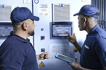 Leadec employees in front of screen of boiler plant.