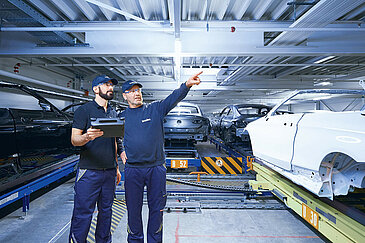 Two Leadec employees monitoring the automated conveyor technology using a tablet.